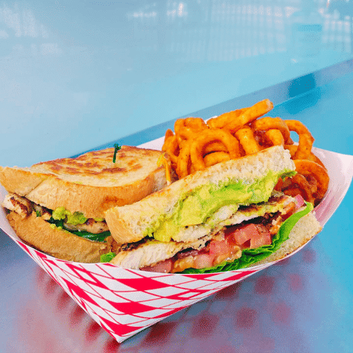 Grilled chicken sandwich with avocado and curly fries.